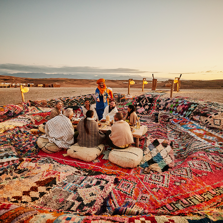 turisti seduti nel deserto di Agafay al tramonto, Marocco