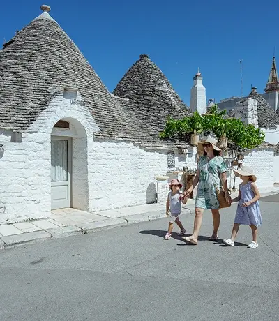 Madre con i bambini che viaggiano e si godono la vacanza in città ad Alberobello, Puglia, Italia
