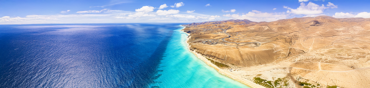 vista aerea sulla costa di Fuerteventura con paesaggio vulcanico e mare azzurro chiaro e scuro, isole Canarie, Spagna
