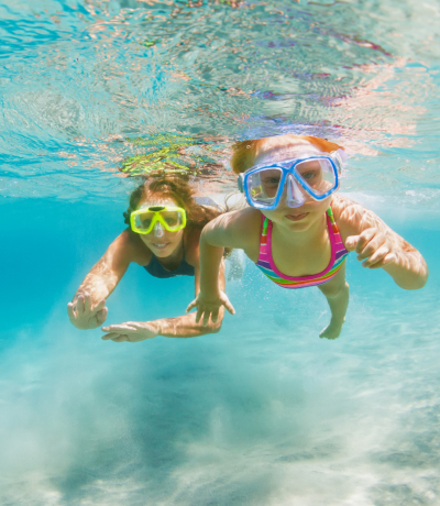 Mamma e figlia che nuotano in acque cristalline 