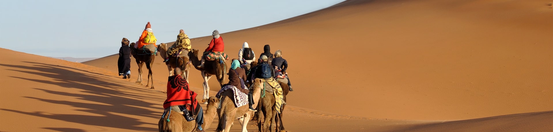 turisti nel deserto durante una passeggiata con carovana di cammelli Marocco