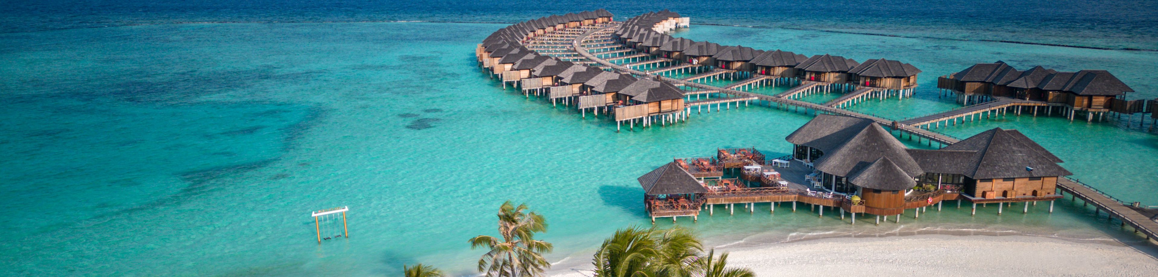 vista aerea su spiaggia paradisiaca di sabbia bianca e mare azzurro cristallino dove si scorgono bungalows sull'acqua Maldive